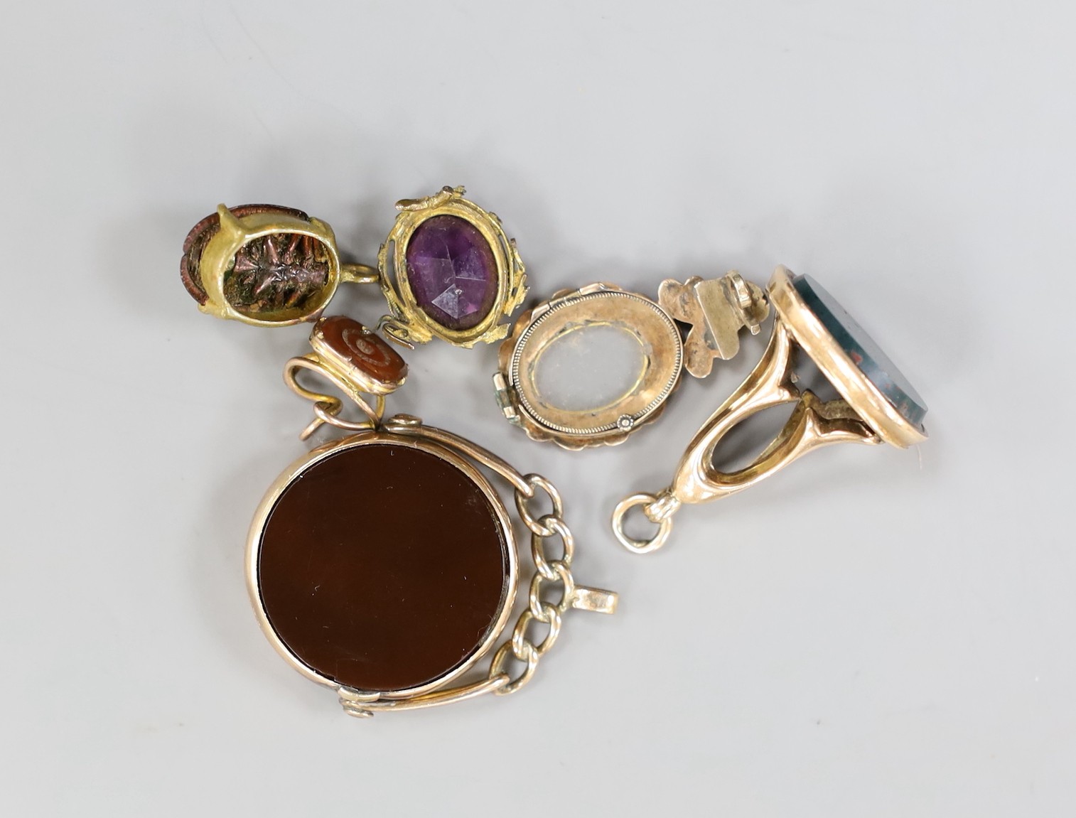 A late Victorian 9ct gold mounted carnelian and bloodstone set spinning fob seal, diameter 23mm, a later 9ct gold and bloodstone fob seal and four other items.